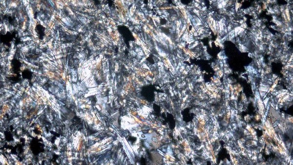 Mikrofotografie amfibolového (kontaktního) rohovce z oblasti Jistebska. Jehlice aktinolitu vzájemně prorůstají, čímž zajišťují maximální pevnost horniny. Spolu s živcem a černými zrny ilmenitu tvoří hlavní minerály horniny. Foto ve zkřížených nikolech, spodní strana obrázku je 0,57 mm. Mikrofotografie amfibolového (kontaktního) rohovce z oblasti Jistebska. Jehlice aktinolitu vzájemně prorůstají, čímž zajišťují maximální pevnost horniny. Spolu s živcem a černými zrny ilmenitu tvoří hlavní minerály horniny. Foto ve zkřížených nikolech, spodní strana obrázku je 0,57 mm.