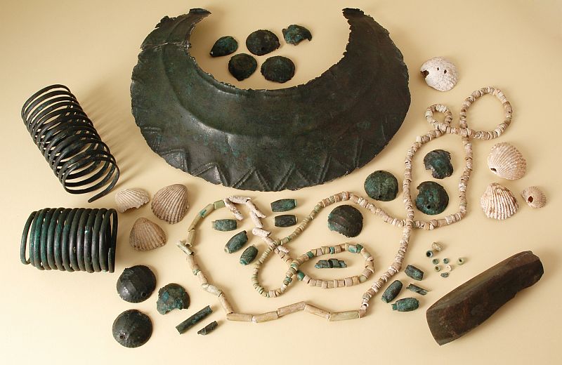 Fotografie. Mimořádně bohatý soubor obsahující velký počet ozdob z mědi pochází ze skříňkového hrobu z Velvar a je datován do doby kolem roku 3200 př. n. l. V pozdní době kamenné (eneolitu), ze které hrob pocházel, se na našem území teprve poskrovnu objevovaly první měděné výrobky. Foto L. Káchová.