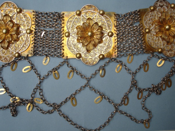 Pás stříbrný filigránový, částečně pozlacený, unikátní filigránová práce. Pás má puncovní značku „EW“ – zlatník Emil Wotke, který působil přímo v Těšíně (1855–1924). V 8568, ošetřeno.  Zlatník Emil Wotke vynikal zejména svými filigránovými pásy, lancušky a háčky. Těšínské Slezsko, 2. polovina 19. století. Etnografické oddělení Národního muzea, H4-103843. Zdroj: Monika Tauberová 2012