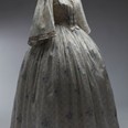 Šaty dámské bílé s drobným fialovým květinovým vzorem, tištěné jemné bavlněné plátno – mušelín, 1850–1860. Šaty pravděpodobně patřily principálce kočovné herecké společnosti Elišce Zöllnerové.